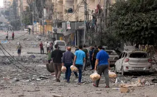 ¿Cómo ayudar a los damnificados por el conflicto entre Israel y Palestina? Hombres palestinos llevan pan a través de una calle fuertemente bombardeada después de los ataques aéreos israelíes en la ciudad de Gaza el 10 de octubre de 2023.
