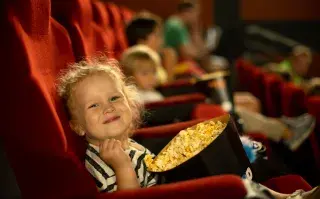 Nena comiendo pochoclos en el cine