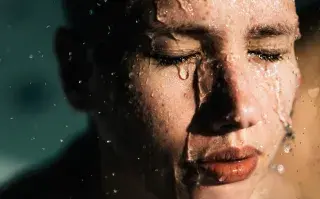 Agua marina en tu rutina de skincare: ¿cuáles son sus beneficios para la piel? Mujer con el rostro salpicado de agua.