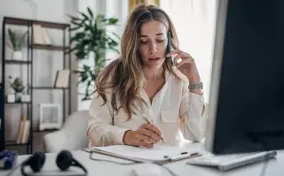 Cuánto tiempo hay que hacer ejercicio para combatir el sedentarismo, según un estudio Una mujer trabajando mientras habla por teléfono