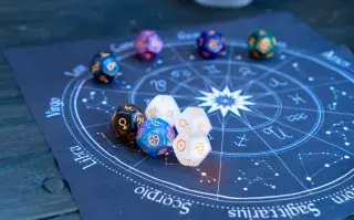 La rueda zodiacal, con los símbolos de los 12 signos astrales en un lienzo y encima, unos dados de planetas.