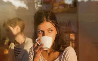 "Napuccino": así es la nueva tendencia recomendada por expertos para dormir la siesta Un mujer tomando una taza de café mirando por la ventana