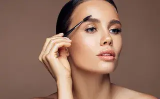 Una mujer peinándose las cejas con un cepillo