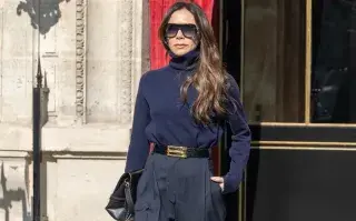 Victoria Beckham caminando por la calle con un look azul marino muy elegante