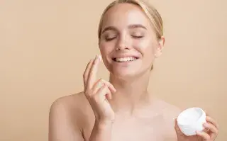 Foto de una mujer poniéndose crema hidratante en el rostro.