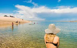 La playa escondida que es considerada el “Caribe argentino” y enamora a los turistas con sus aguas cristalinas Una mujer en la playa de espaldas con un sombrero