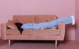 El "gran cansancio": ¿de qué se trata esta tendencia y cómo cambiarán nuestros consumos? Una mujer cansada tirada acostada en un sillón.