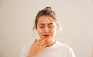Una mujer aplicandose crema en la cara