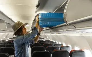 Una mujer con un carry on en el avión