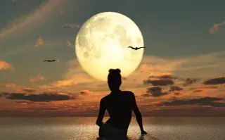 Una mujer mirando una Luna Llena desde el agua.