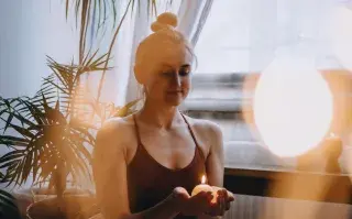 Una mujer sosteniendo una vela entre sus manos.