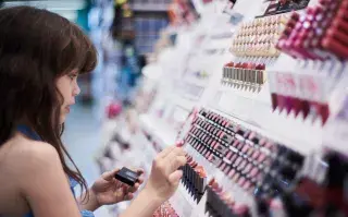 Cómo armar un kit completo de maquillaje sin gastar de más Una mujer eligiendo maquillaje en un comercio