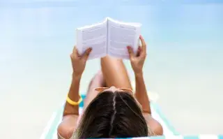 Una mujer leyendo en la playa