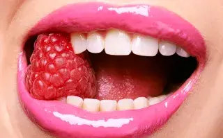 Una mujer comiendo una frambuesa