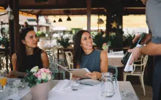 mozo y dos mujres en un restaurante