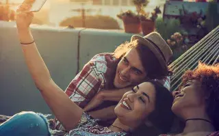 ¿Las nuevas generaciones ya no toman alcohol?: quiénes son los neoabstemios jóvenes sonriendo frente al celular