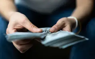 Foto de mujer ordenando billetes.