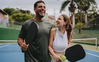 Después del boom del pádel, llega el pickeball: así es el deporte tendencia que practican Leo Di Caprio y Kim Kardashian Dos personas con paletas y pelotas de pickeball