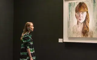 Chloe mirando a la pared dónde hay un cuadro de pintura de una mujer colorada