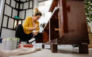 Foto de mujer reparando un mueble antiguo.