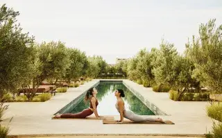 Dos chicas haciendo yoga enfrente de una pileta