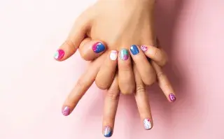 Dos manos entrelazadas con uñas de colores