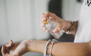 Una mujer poniendose perfume en la muñeca