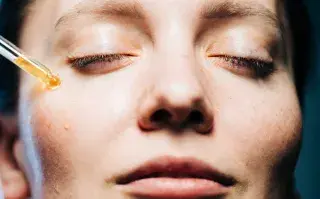 Hola invierno: ¿por qué hablamos de renovación de la piel cuando llega el frío? una mujer con un gotero aplicandose un serum en el rostro