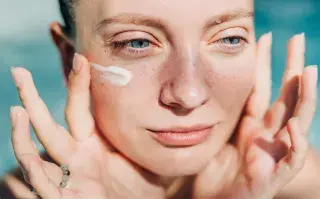 Una mujer poniendose una crema en la cara