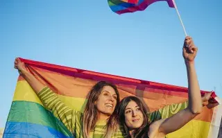 dos mujeres con una bandera de la diversidad sexual