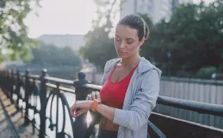 Entrenadores lo confirman: por qué las rutinas cortas de 20 minutos rinden más que una hora de gimnasio en invierno mujer mira el reloj para controlar el tiempo de entrenamiento