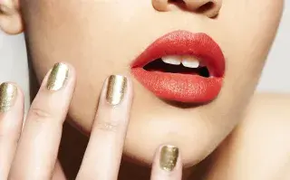 Tendencias 2026: los labios full color se convierten en los grandes protagonistas del maquillaje Una mujer con los labios en color rojo y las uñas doradas