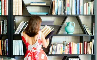 Bookshelf wealth: la tendencia deco que convierte los libros en protagonistas del living Foto de mujer leyendo un libro.