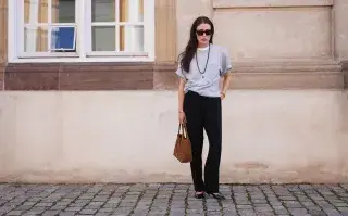 Los pantalones negros de los años 90 volverán a estar de moda: ¿cómo vamos a usarlos? Una mujer parada en la calle con remera corta y pantalones negros