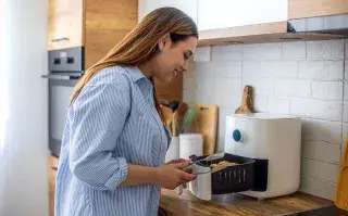 Estos son los electrodomésticos que consumen más energía eléctrica (y quizás no lo sabías) Freidora de aire y una mujer en la cocina