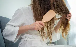 ¿Pelo fino y dañado? Los hábitos que ayudan a recuperar el volumen y la densidad, según un experto Una mujer peinándose en bata