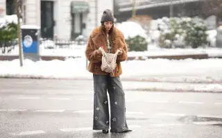 Vestirse en capas para el fin de semana: las combinaciones que abrigan con mucho estilo Una mujer con un jean gris y un saco de pelo en color marrón