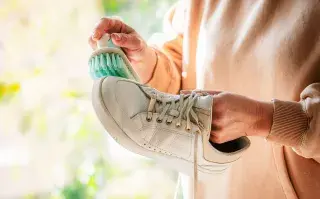 Cómo eliminar el mal olor de calzados y zapatillas Mano lavando zapatilla de cuero blanca