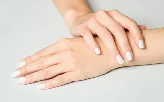 Manos pintadas con esmalte color crudo sobre fondo blanco