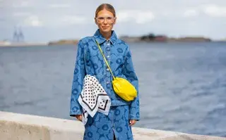 Los cuatro accesorios que serán imprescindibles este verano Una mujer con un conjunto de denim con flores, una cartera amarilla y un pañuelo en la cintura