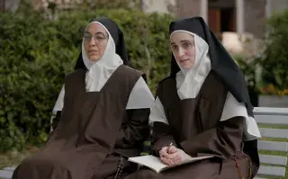 Dos monjas sentadas en un banco de un convento.