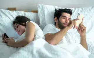 pareja en cama con celular