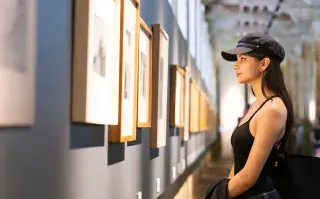 Mujer observando cuadros en una muestra de arte.