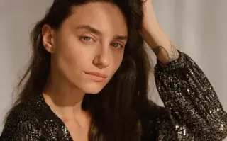 Cómo maquillar las cejas sin exagerar: qué recomiendan los maquilladores expertos Una mujer posando con un traje con brillos y cejas prominentes
