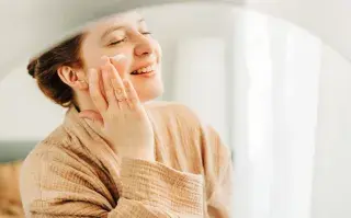 Una mujer poniéndose crema en la cara