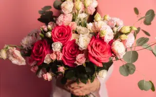 Una mujer con un ramo de flores en la mano- son rosas blancas y rojas
