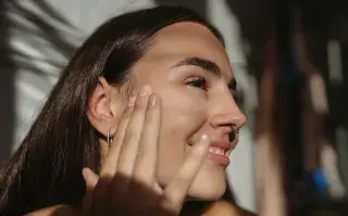 Una mujer haciéndose el skincare en el baño
