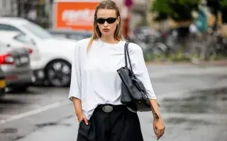 Una joven parada en la calle con lentes de sol