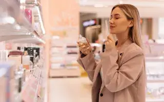 Una mujer oliendo perfumes en una góndola de perfumería