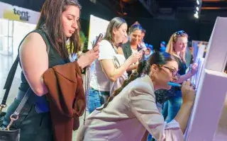Chicas escribiendo en una pared y grabando con el celular.